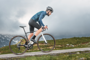 A healthy cyclist ascends a mountain road on an overcast day.