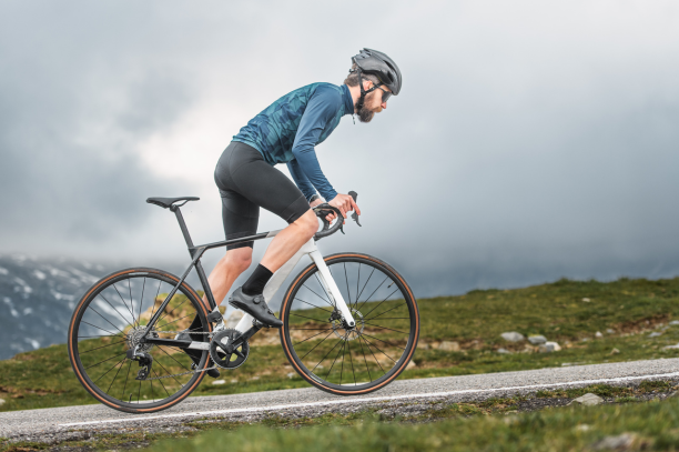 A healthy cyclist ascends a mountain road on an overcast day.