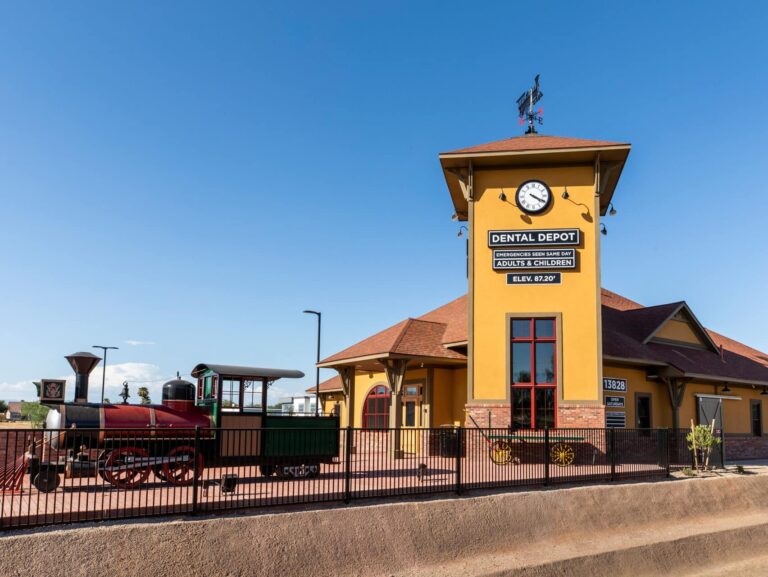 Exterior view of Surprise dentist office with yellow exterior, model train, and clock tower 2