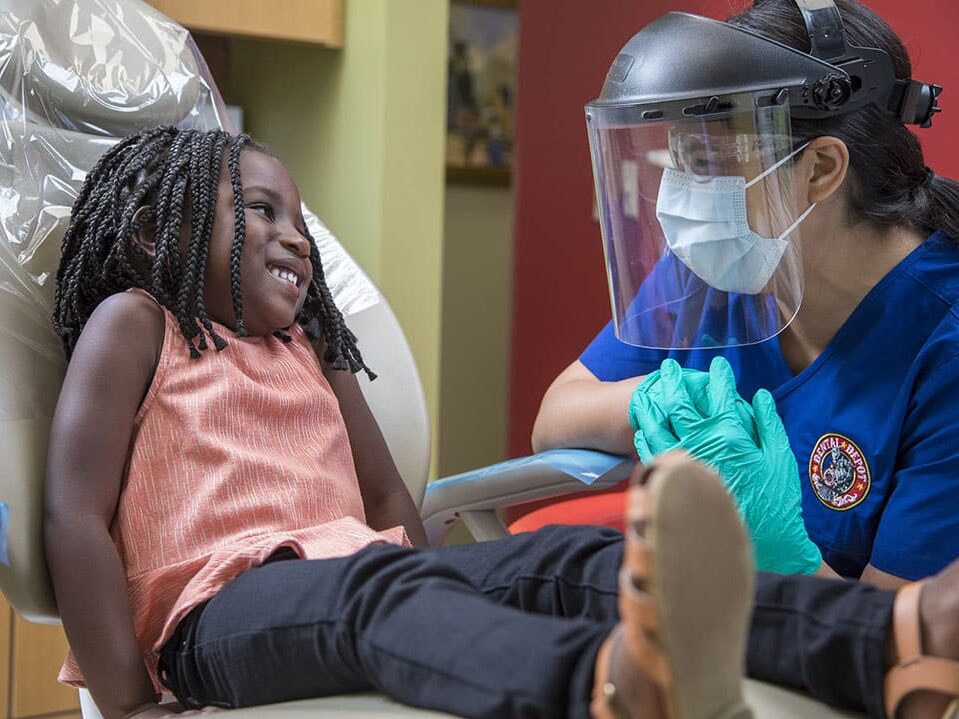 A small child talks with a dental hygienist at dental depot