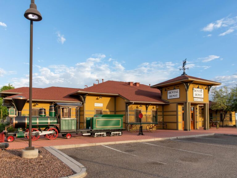 Exterior view of the Phoenix dentist office with a green train model and yellow exterior.