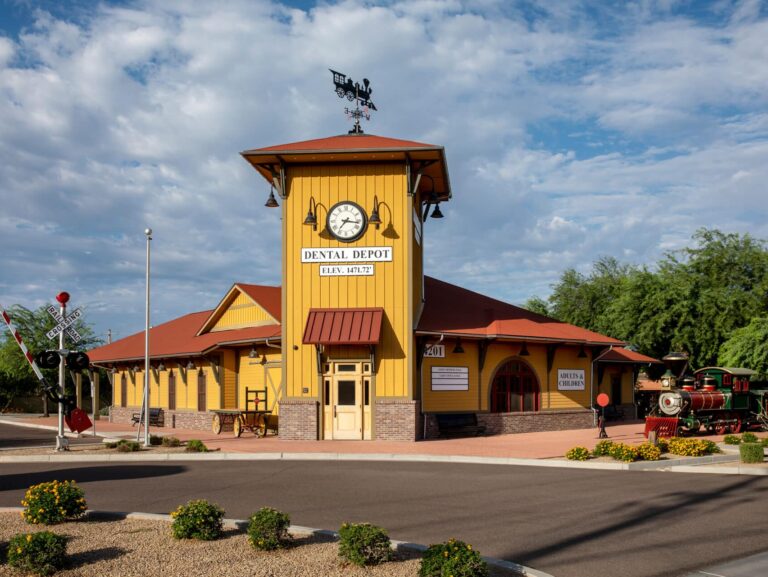 Exterior view of the Dental Depot dentist office in Northeast Phoenix with a clock tower, red roof, and yellow exterior.