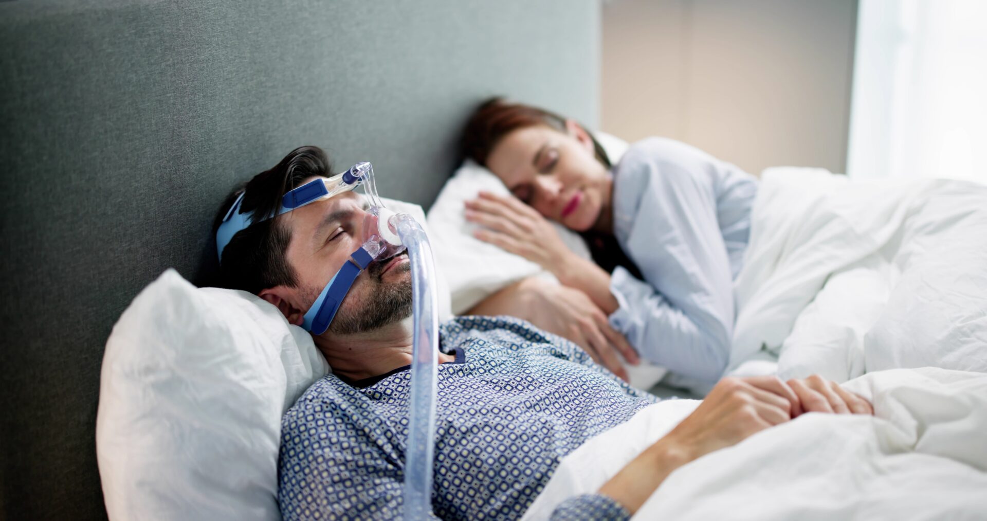 Man wearing sleep apnea mask is sleeping soundly next to his wife.