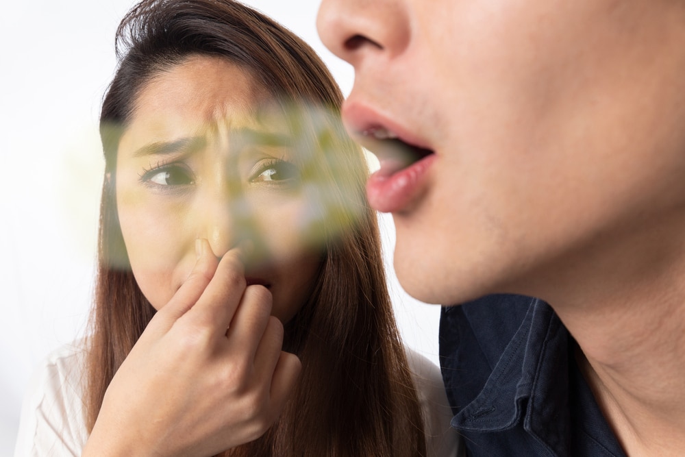 Women pinching her nose because a man has bad breath