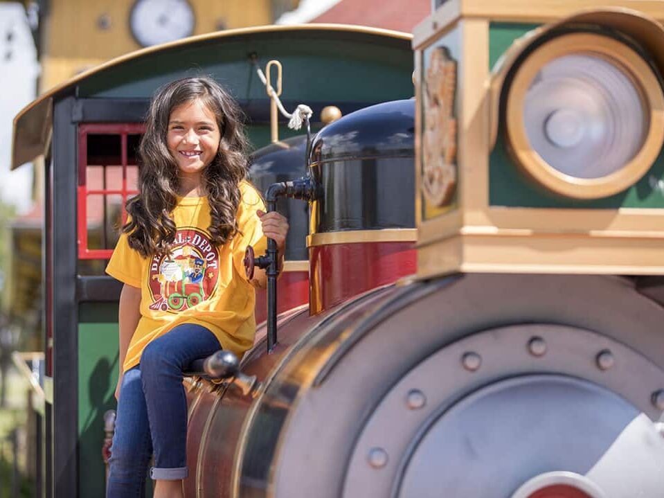 A young girl smiles sitting on the train at dental depot.